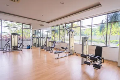 a gym with treadmills and exercise equipment in a room with windows at Peaceful 3-bedroom with Pool 5 pax - Wangsa Maju in Kuala Lumpur