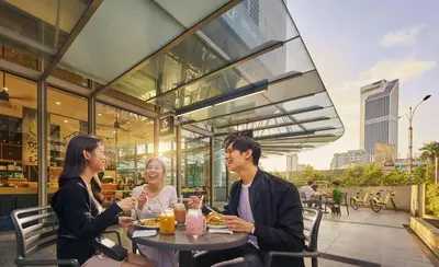 three people sitting at a table outside a restaurant at Robertson Suites Bukit Bintang with Netflix in Kuala Lumpur