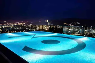 a large blue swimming pool on the roof of a building at night at Flexi check in 10min to KLCC next to Hospital Gleneagle in Kuala Lumpur