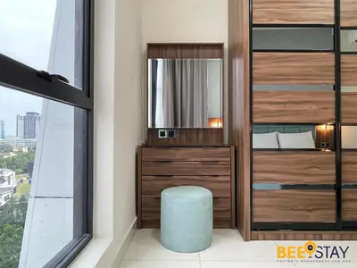 a bedroom with a wooden dresser and a mirror at Arte Mont Kiara Studio by BeeStay in Kuala Lumpur