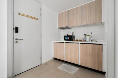 a kitchen with white walls and wooden cabinets at Una serviced Apartment in Kuala Lumpur