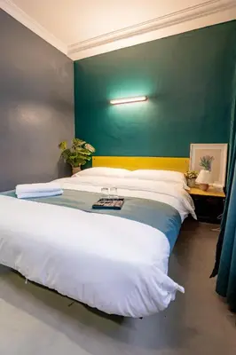 a bedroom with a large white bed with a green wall at Hotel 28 Chow Kit Kuala Lumpur in Kuala Lumpur