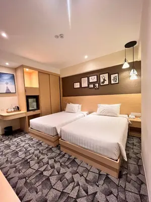 a hotel room with two beds and a desk at Hotel Damai Kuala Lumpur in Kuala Lumpur