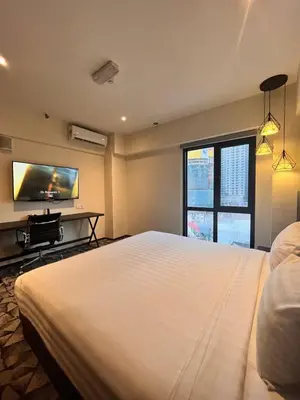 a bedroom with a large white bed and a flat screen tv at Hotel Damai Kuala Lumpur in Kuala Lumpur