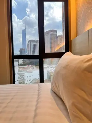 a bed with a view of a city from a window at Hotel Damai Kuala Lumpur in Kuala Lumpur