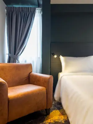 a bedroom with a bed and a chair next to a window at Trigo Hotel Kuala Lumpur in Kuala Lumpur