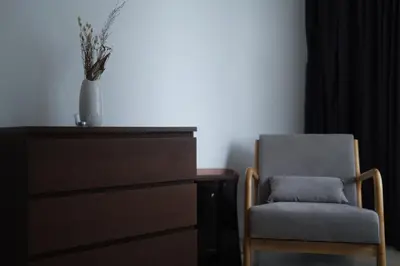 a chair sitting next to a dresser with a vase at Atmoods - Vortex KLCC in Kuala Lumpur