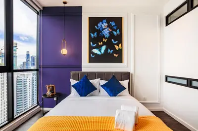 a bedroom with purple walls and a bed with blue pillows at Scarletz Suites KLCC by Mana-Mana in Kuala Lumpur