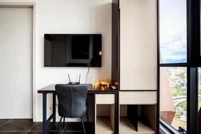 a room with a desk with a chair and a tv at Scarletz Suites KLCC by Mana-Mana in Kuala Lumpur