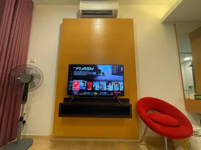 a room with a tv in a wall with a red chair at Staycation with Private Jacuzzi @ KL Downtown 1711 in Kuala Lumpur