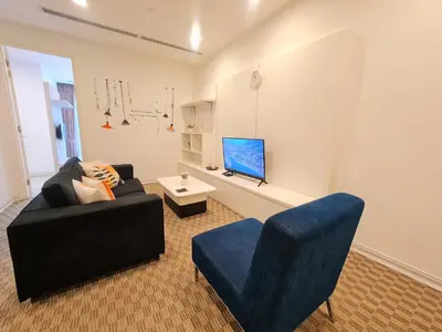 a living room with a black couch and a blue chair at KLCC Binjai 8 Premium Soho Apartment by Sarah's Lodge in Kuala Lumpur