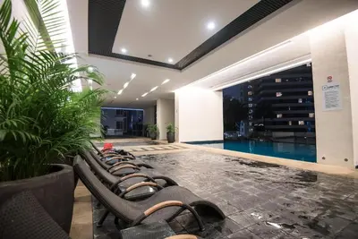 a row of chaise lounge chairs next to a swimming pool at KLCC Binjai 8 Premium Soho Apartment by Sarah's Lodge in Kuala Lumpur