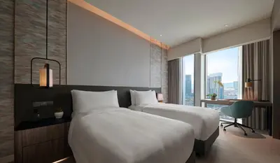 a hotel room with two beds and a window at Pan Pacific Serviced Suites Kuala Lumpur in Kuala Lumpur