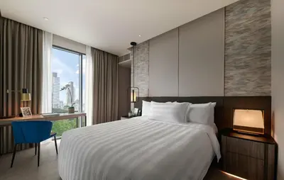 a hotel room with a bed and a desk and a window at Pan Pacific Serviced Suites Kuala Lumpur in Kuala Lumpur