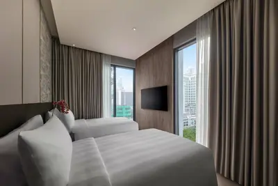 a hotel room with two beds and a window at Pan Pacific Serviced Suites Kuala Lumpur in Kuala Lumpur