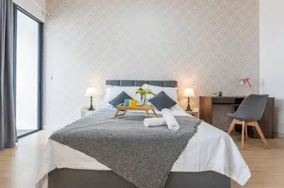 a bedroom with a bed with a table and a chair at Cozy Oasis near Ikea TRX Mall King Size Bed 100mb in Kuala Lumpur