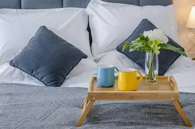 a tray with a vase of flowers and two cups on a bed at Cozy Oasis near Ikea TRX Mall King Size Bed 100mb in Kuala Lumpur