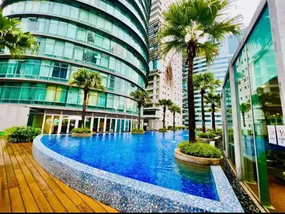 a large building with a pool in front of it with palm trees at near klcc vortex suites by PLUS POIN in Kuala Lumpur