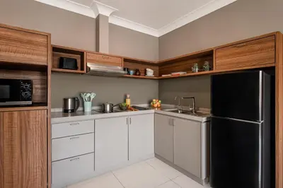 a kitchen with white cabinets and a black refrigerator at Domitys Bangsar Kuala Lumpur in Kuala Lumpur