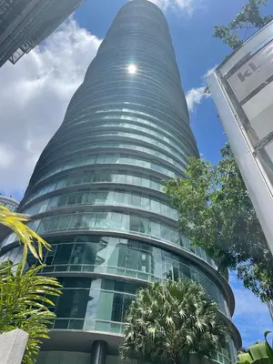 a tall glass building with trees in front of it at KLCC vortex apartment suites Kuala Lumpur in Kuala Lumpur