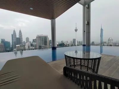 a balcony with a glass table and a view of the city at Colony ( Wisma Infinitum ) in Kuala Lumpur