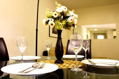 a table with glasses and a vase of flowers on it at D'CASA Fairlane 
