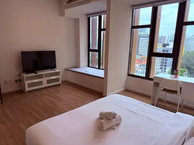 a bedroom with a bed and a tv and windows at Ceylonz Suites by ROOMY in Kuala Lumpur