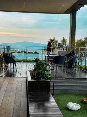 a man standing on a deck with a table and chairs at STAR RESIDENCE KLCC in Kuala Lumpur