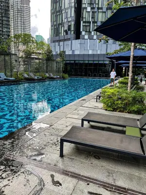 a swimming pool with two benches and an umbrella at STAR RESIDENCE KLCC in Kuala Lumpur