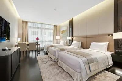 a hotel room with three beds and a dining room at Banyan Signatures Pavilion Kuala Lumpur in Kuala Lumpur