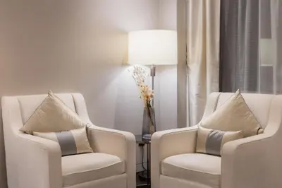 a room with two chairs and a table with a lamp at Banyan Signatures Pavilion Kuala Lumpur in Kuala Lumpur