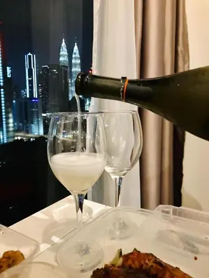 a person pouring wine into two wine glasses on a table at Expressionz Professional Suites by AURORA SUMMER SUITES in Kuala Lumpur