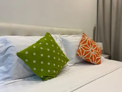 two green pillows sitting on top of a bed at One Bukit Ceylon by Home Suites in Kuala Lumpur