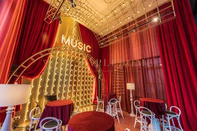 a room with red curtains and a stage with tables and chairs at Scarletz Premier Suites Kuala Lumpur in Kuala Lumpur