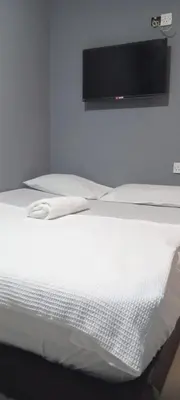 a white bed with a television on a wall at RAS International Hotel in Kuala Lumpur