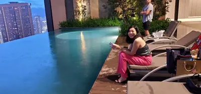 a woman sitting next to a pool on top of a building at Lucentia Lalaport BBCC, Stuning Infinity Pool in Kuala Lumpur