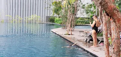 a woman sitting next to a swimming pool at Lucentia Lalaport BBCC, Stuning Infinity Pool in Kuala Lumpur