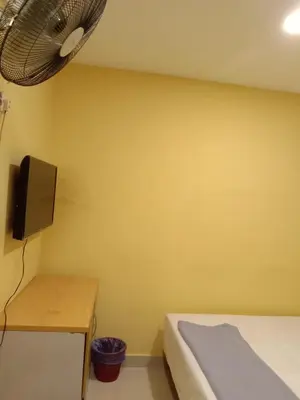 a bedroom with a yellow wall with a bed and a desk at RAS Hotel in Kuala Lumpur
