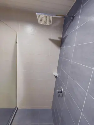 a bathroom with a shower with a tile wall at AJ-HOME Fahrenheit 88 Pavillion Bukit Bintang 8pax in Kuala Lumpur