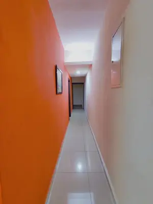 a hallway with orange walls and white tiles at AJ-HOME Fahrenheit 88 Pavillion Bukit Bintang 8pax in Kuala Lumpur
