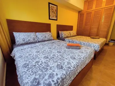 two beds in a bedroom with yellow walls at AJ-HOME Fahrenheit 88 Pavillion Bukit Bintang 8pax in Kuala Lumpur