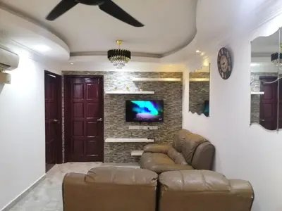 a living room with a couch and a tv on a wall at Apartment Low Cost 2 Bilik Asnor Homestay KL in Kuala Lumpur