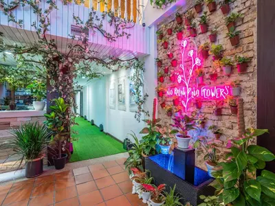 a room with plants and a brick wall with a neon sign at Floresta Hotel Chinatown in Kuala Lumpur
