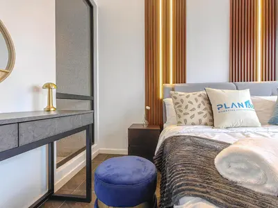 a bedroom with a bed with a blue stool and a mirror at Scarletz Suites by Stevvy KL Home Stay in Kuala Lumpur