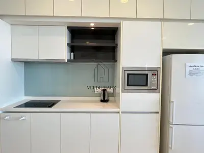a white kitchen with a microwave and a refrigerator at The Platinum KLCC by Veedu Hauz in Kuala Lumpur
