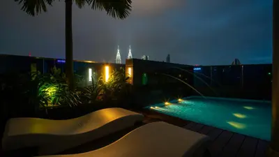 a balcony with a swimming pool at night at MOONWAY SUITES At EATON KLCC in Kuala Lumpur