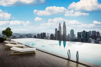 a infinity pool with chairs and a city skyline at THE FACE Style Hotel in Kuala Lumpur