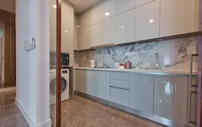 a kitchen with white cabinets and a washer and dryer at THE FACE Style Hotel in Kuala Lumpur