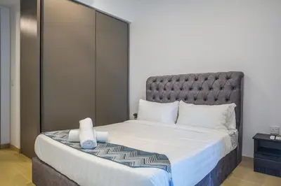 a bedroom with a large bed with a gray headboard at Eaton Residence KLCC Skyline in Kuala Lumpur