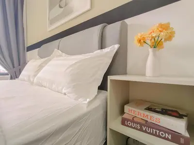 a bed with a white pillow and a vase with flowers at M Vertica By Minsu in Kuala Lumpur